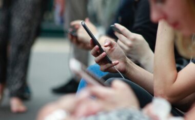 A close up photo of people's hands, holding cell phones.