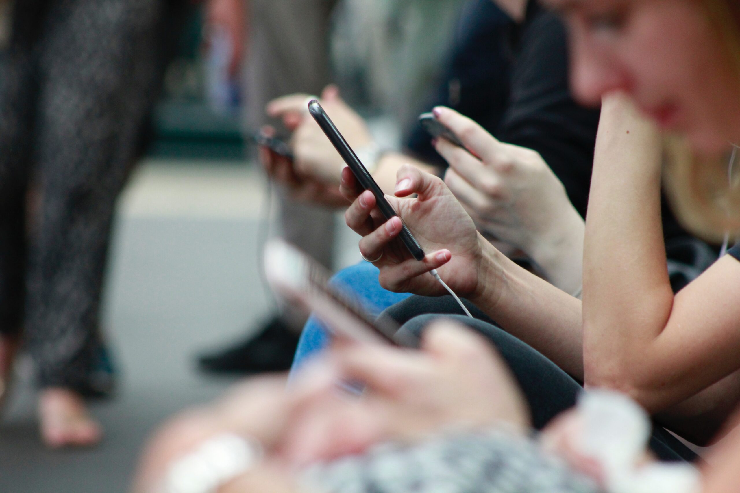 A close up photo of people's hands, holding cell phones.