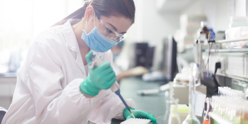 Female Scientist working in a lab with a mask and goggles on