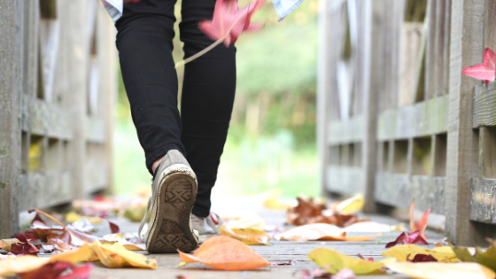 Person walking on bridge with leaves on ground