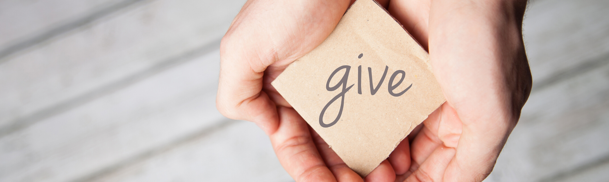 hands holding a block with the word give on it