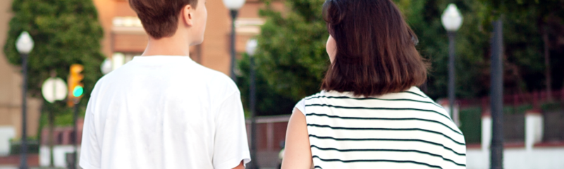 Son and Mother walking towards a green space with trees