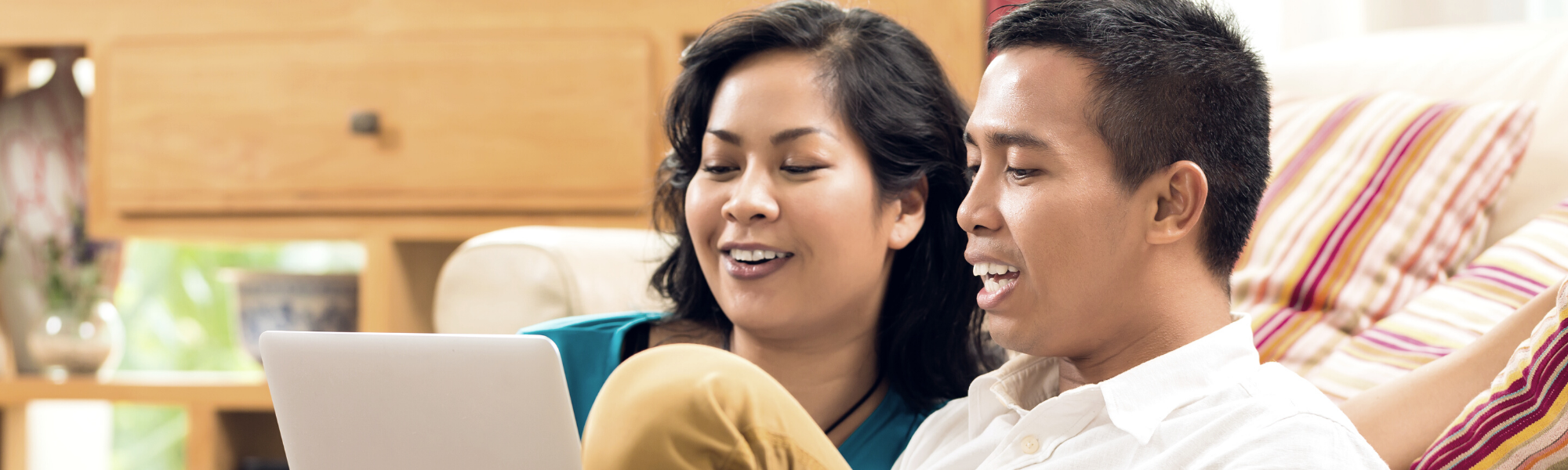 photo of a couple on a couch looking at a screen smiling