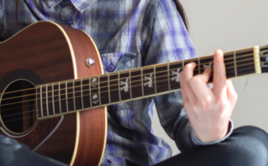 close up of two hands playing a guitar.