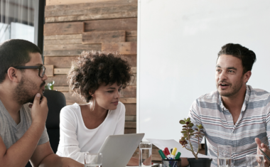 group of young professionals speaking at a desk