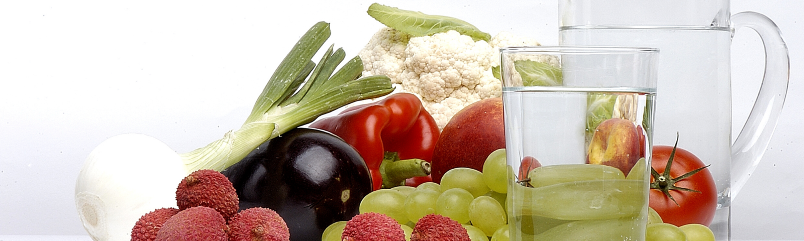 image of a variety of fruits and vegetables on a table with a jug and glass of water