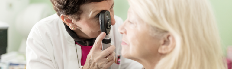 image of an eye doctor examining the eye of a senior patient