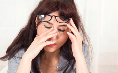 image of young female at desk rubbing her eyes