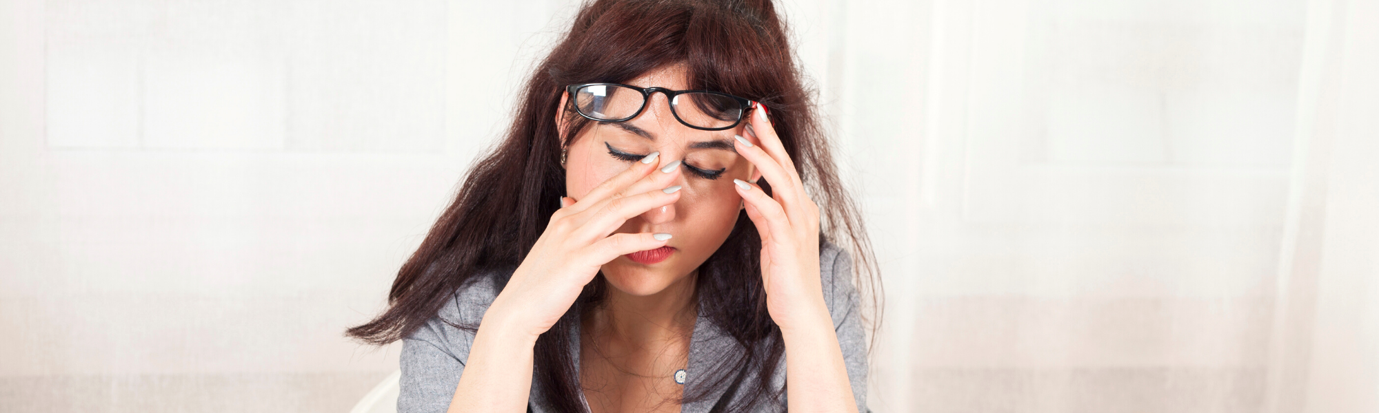 image of young female at desk rubbing her eyes