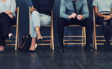 The image is of a group of candidates seated as they await an interview.