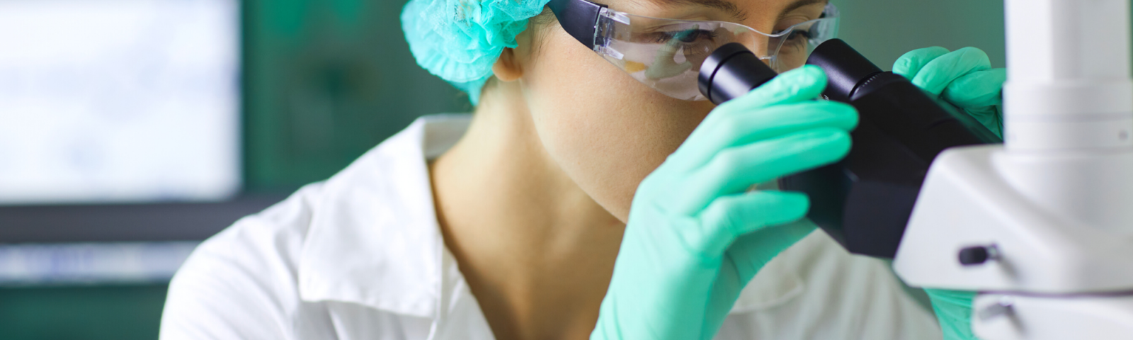 Image is of medical researcher looking through a microscope.