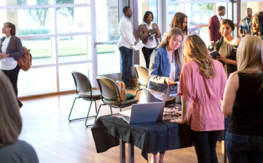 Image is of a group of people networking at an in-person event.