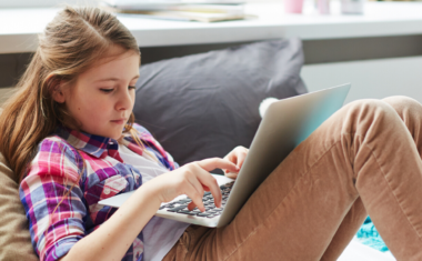 Image is of a teen girl using a laptop