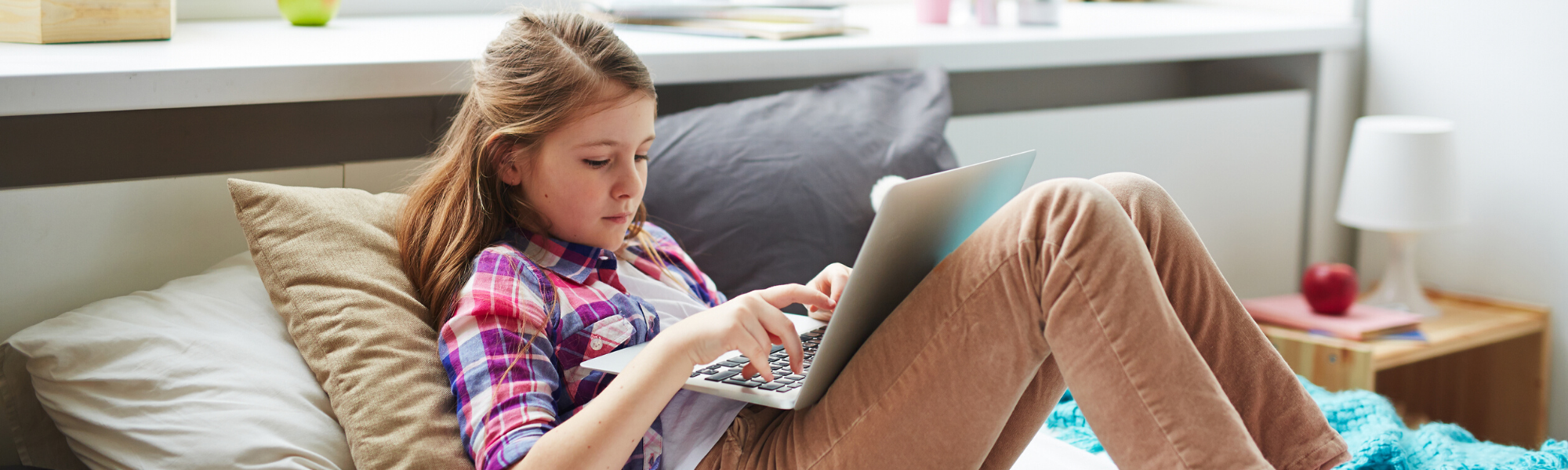 Image is of a teen girl using a laptop