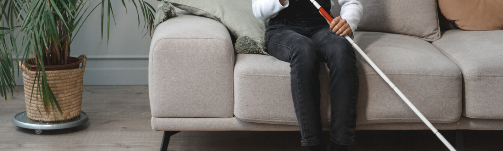 Image is of a woman seating holding a white walking cane