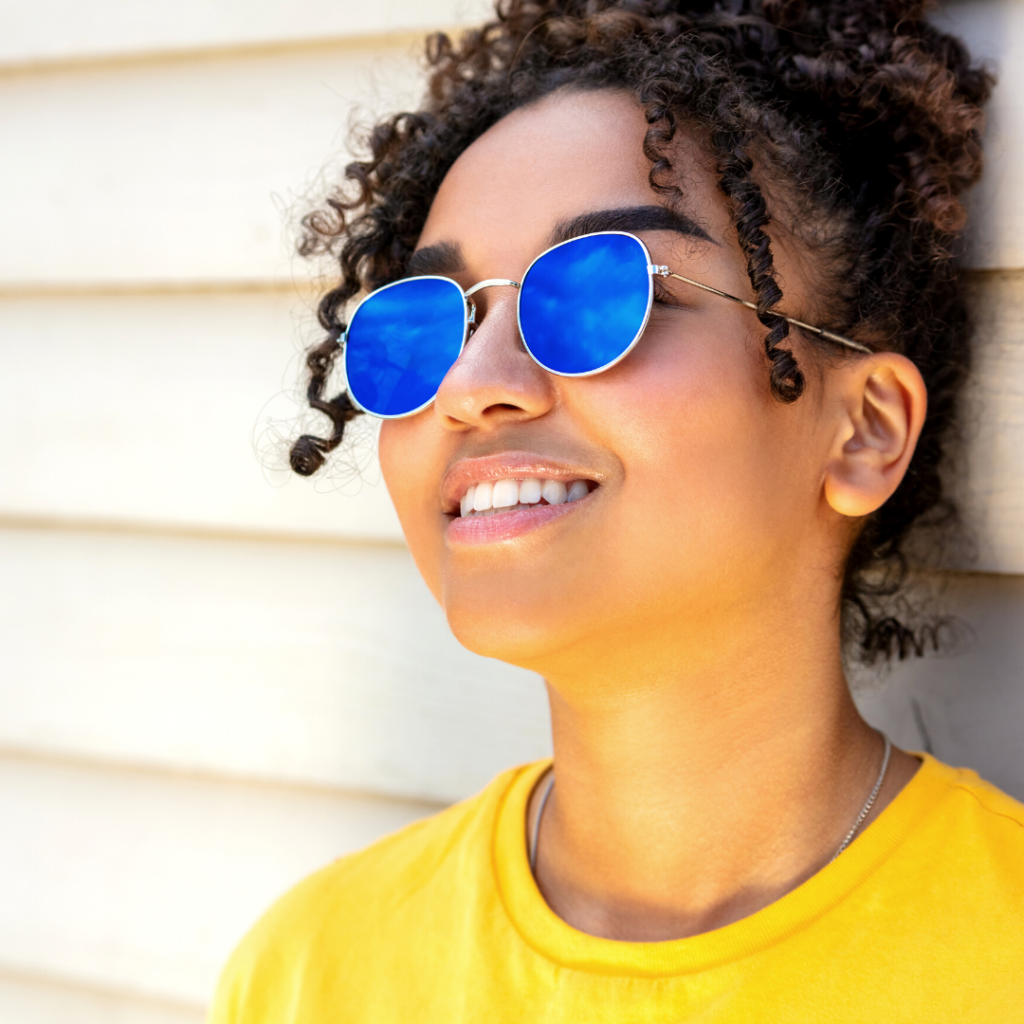 Image is of a woman wearing sunglasses and smiling.