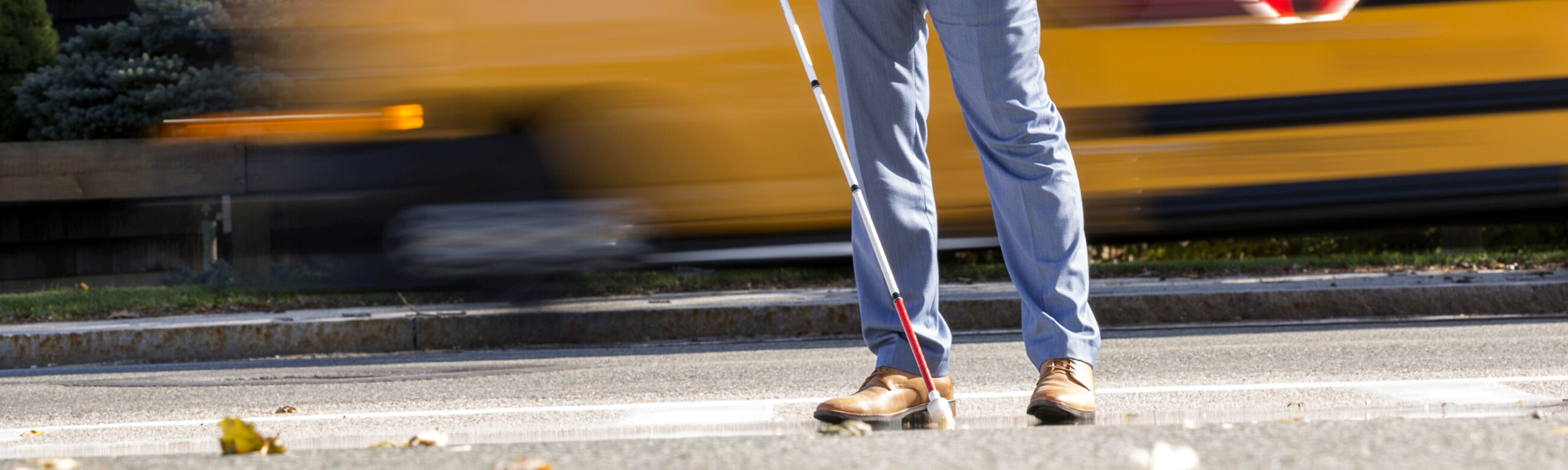 Image is of a professional man walking using a white cane
