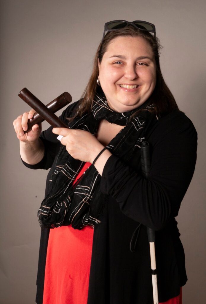 Image is of Amy Amanea holding wooden musical instruments.