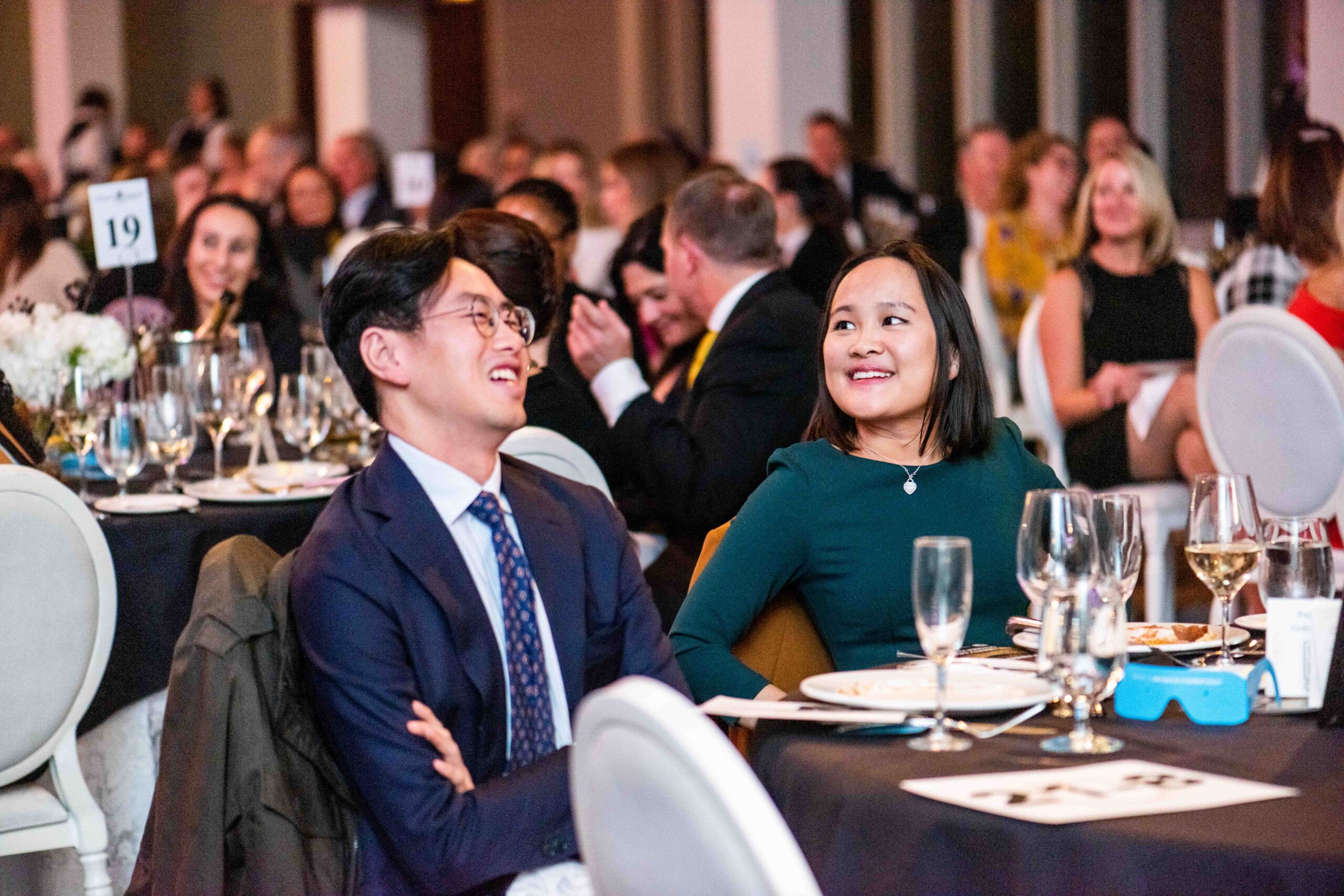 Image is of two event guests seated and laughing.