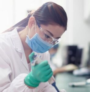 Image is of a lab tech transferring liquids.