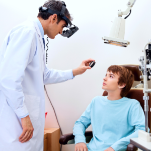 Image is of an eye doctor examining a young male patient.