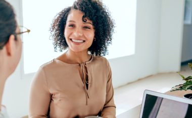 Image is of women smiling during an interview in an office.