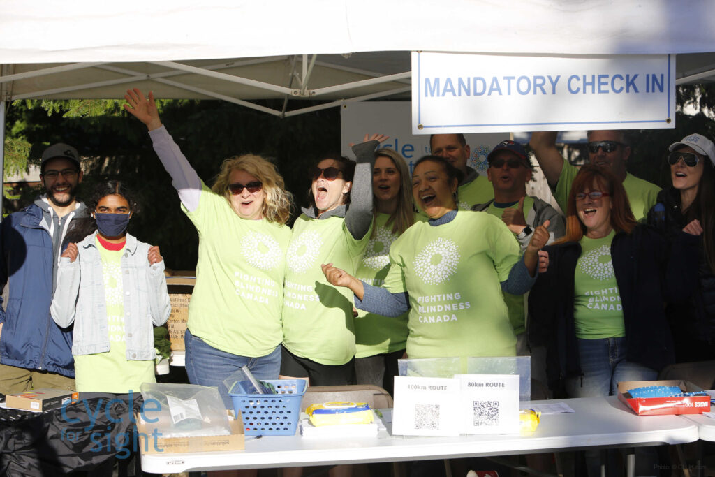 Image is of a group of volunteers laughing, smiling, and cheering during Cycle For Sight Events.