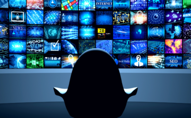 Image is of a chair seating in front of a wall of television monitors displaying a variety of programs.