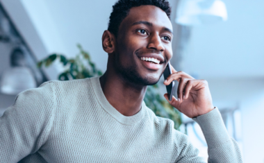 Image is of a man on the phone, smiling.