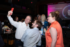 Image is of three event attendees taking a selfie of themselves. They are smiling and standing.
