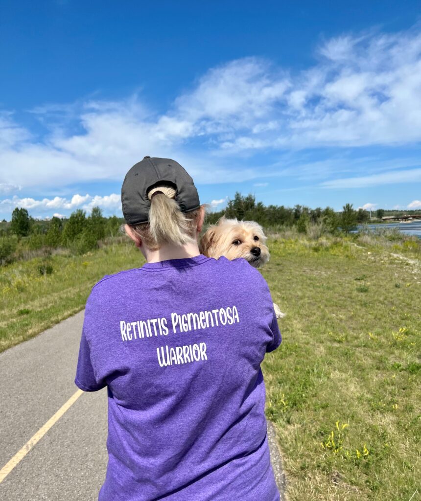 Ashley hall doing  a virtual walk while holding her dog.