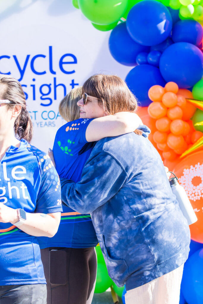 Image is of 2 Cycle for Sight attendees embracing.