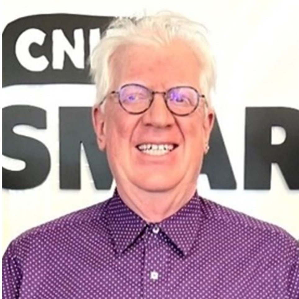 Image of Stephen Ricci wearing a Purple shirt with white polka-dots in front of a sign that says CNIB SmartLife