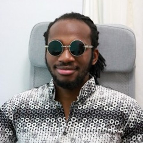 Image of Eitel Houedakor sitting in a chair wearing sunglasses.