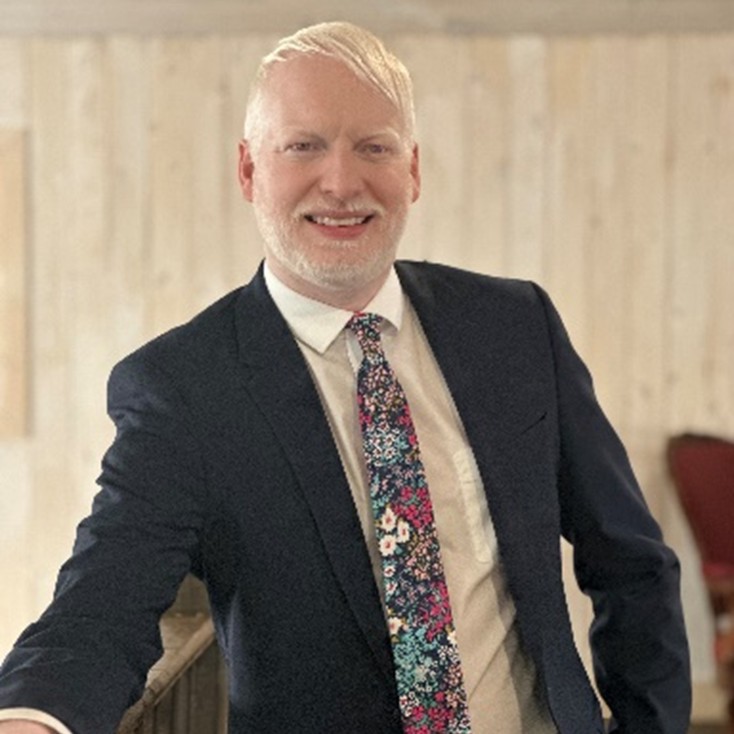 Image of Patrick Losier wearing a white shirt, floral tie and a black blazer.