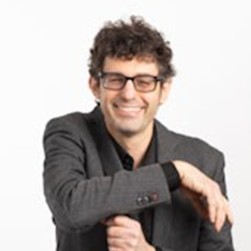 Image of Dr. Stuart Matan-Lithwick, PhD wearing a black shirt with a grey blazer