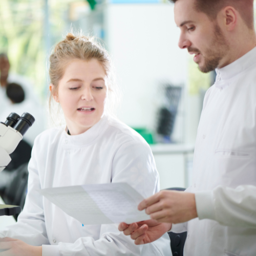woman scientist speaking with man scientist, both looking at a piece of paper