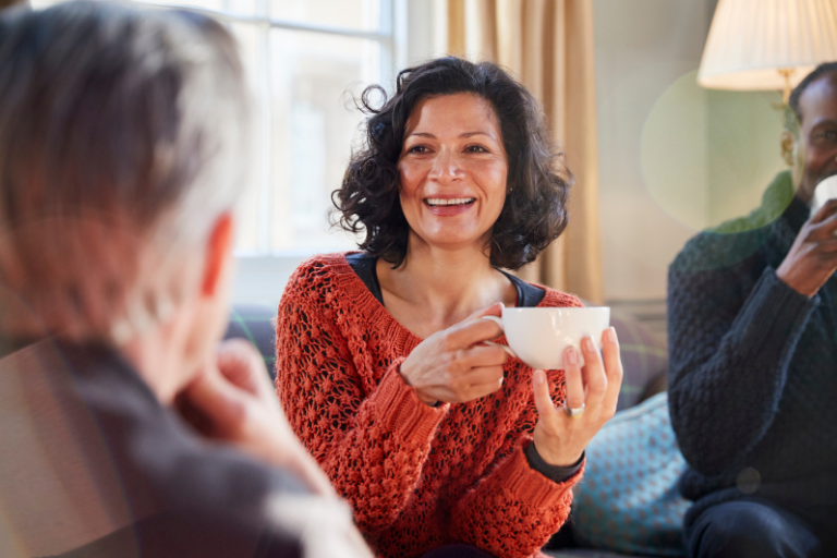 woman holding a white mug, smiling at a person
