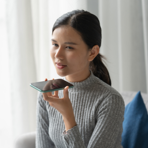 Woman holding her phone up close to her mouth.