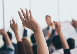 People with their hands up at a lecture