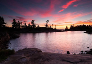 A lake with trees surrounding it. At sunset.