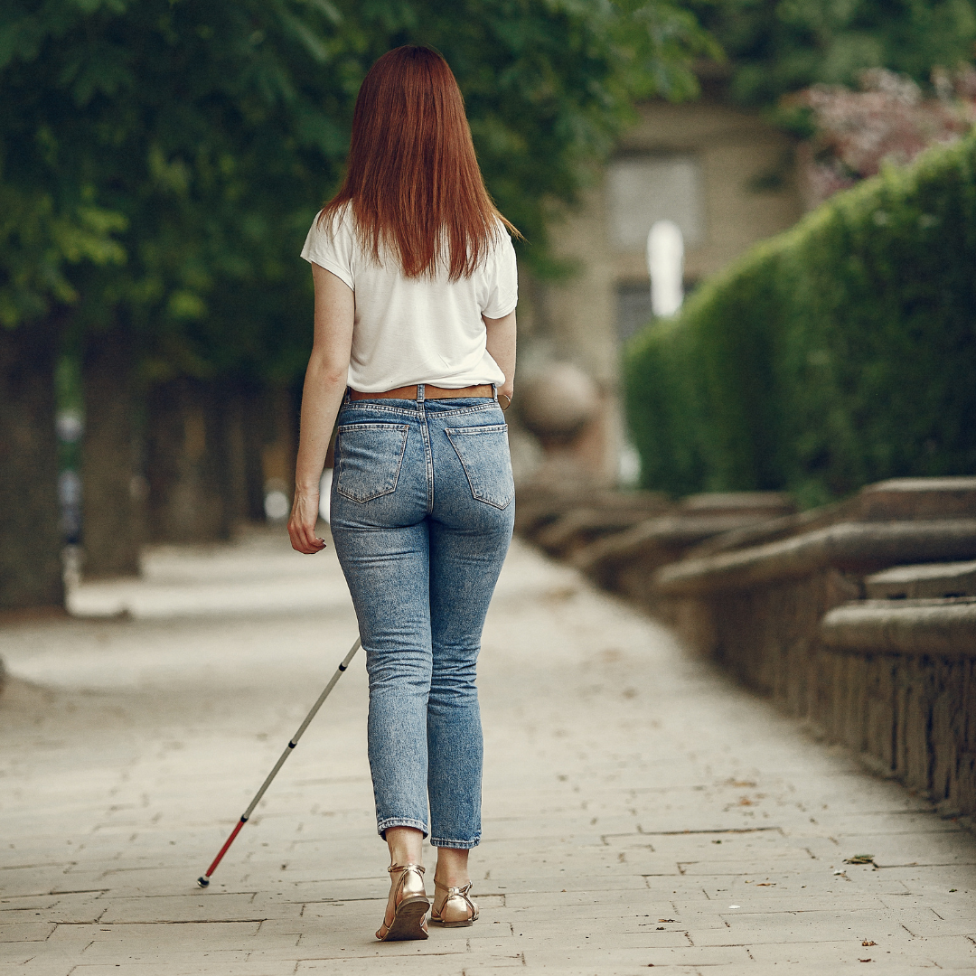 Woman with white cane walking down a street